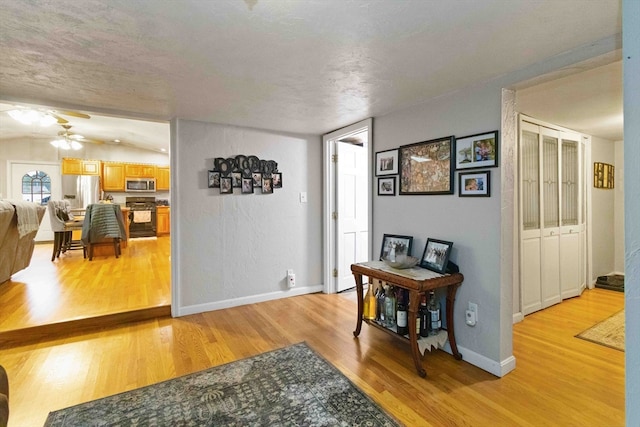 interior space featuring ceiling fan, a textured ceiling, light hardwood / wood-style flooring, and vaulted ceiling