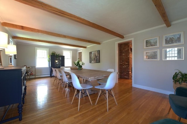 dining area featuring baseboards, a baseboard radiator, beamed ceiling, and wood finished floors