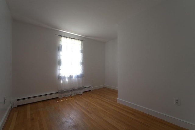 empty room with baseboards, wood finished floors, and baseboard heating