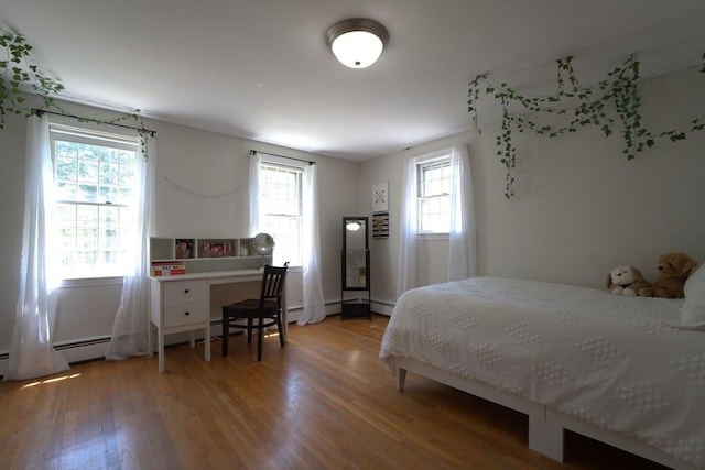 bedroom featuring light wood-style floors, multiple windows, and a baseboard radiator