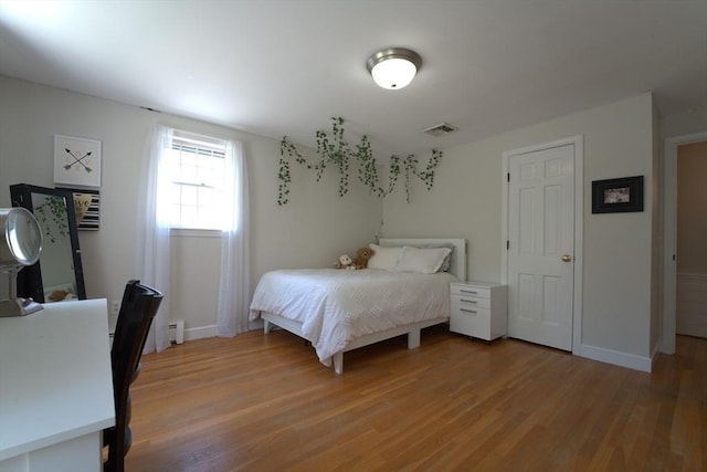 bedroom featuring visible vents, a baseboard radiator, light wood finished floors, and baseboards