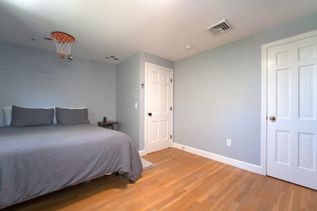 bedroom with visible vents, light wood-style floors, and baseboards