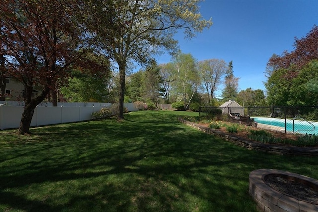 view of yard featuring a fenced in pool, a fenced backyard, and an outdoor fire pit