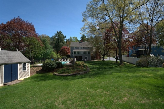 view of yard with a storage shed, an outdoor pool, fence, and an outbuilding