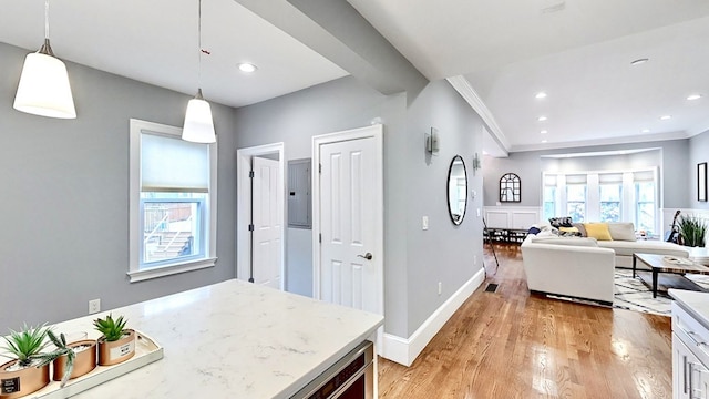 interior space with light hardwood / wood-style floors, ornamental molding, light stone countertops, hanging light fixtures, and electric panel