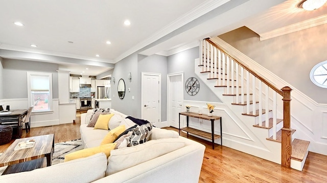 living room featuring ornamental molding, light wood-type flooring, and a healthy amount of sunlight