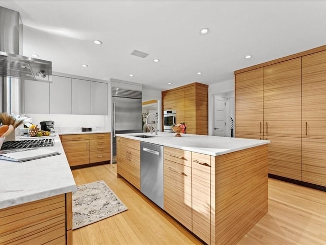 kitchen featuring sink, appliances with stainless steel finishes, white cabinetry, range hood, and a large island with sink