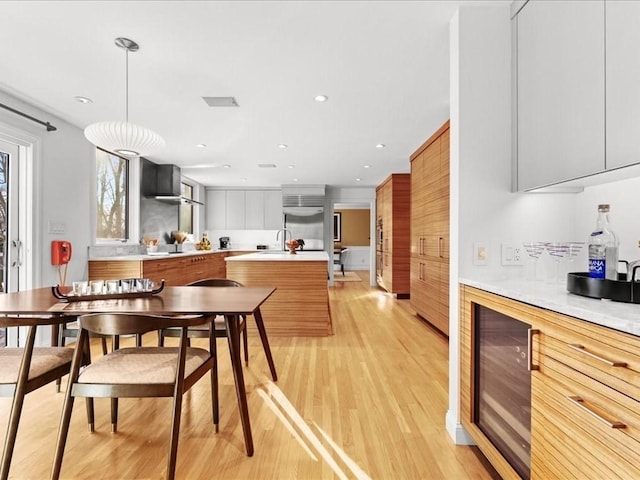 kitchen featuring light hardwood / wood-style floors, hanging light fixtures, beverage cooler, and built in fridge