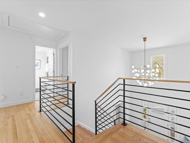 stairway with wood-type flooring and a notable chandelier