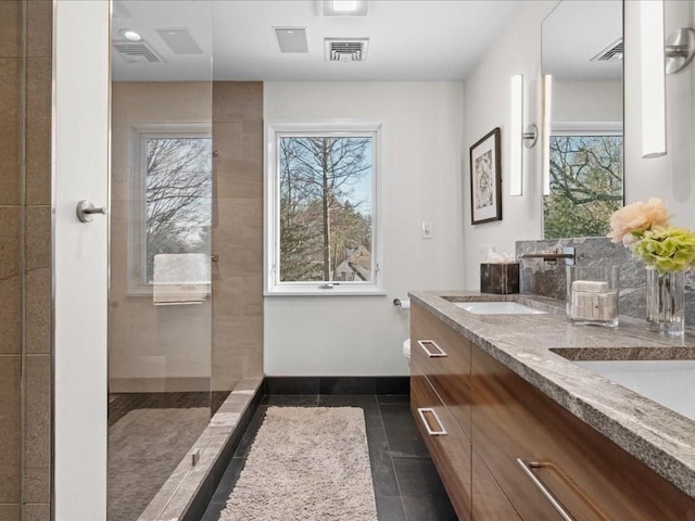 bathroom with vanity, tile patterned flooring, a wealth of natural light, and a tile shower