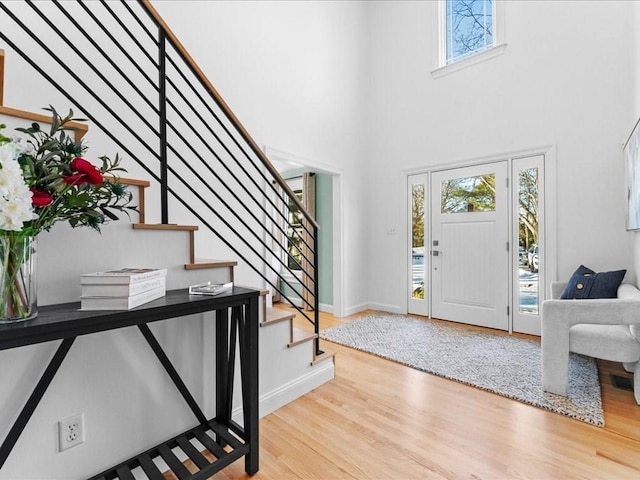 entrance foyer with a towering ceiling, light hardwood / wood-style flooring, and a wealth of natural light