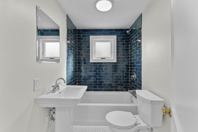 bathroom featuring tile patterned flooring, tiled shower / bath, and toilet