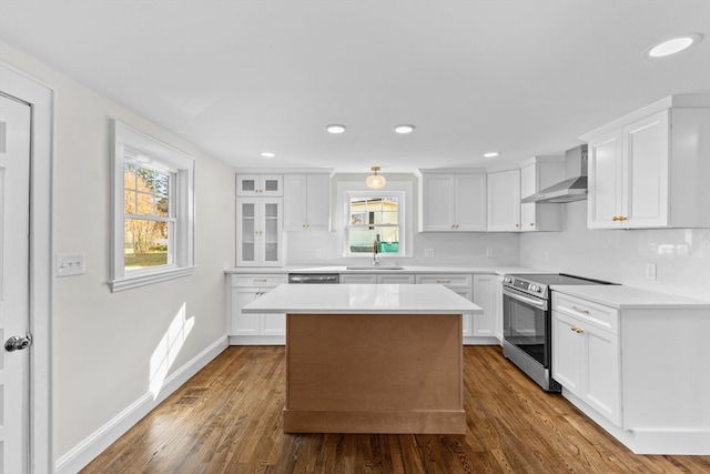 kitchen featuring appliances with stainless steel finishes, dark hardwood / wood-style flooring, a kitchen island, wall chimney range hood, and white cabinetry