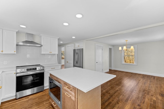 kitchen with white cabinetry, a center island, wall chimney exhaust hood, and appliances with stainless steel finishes