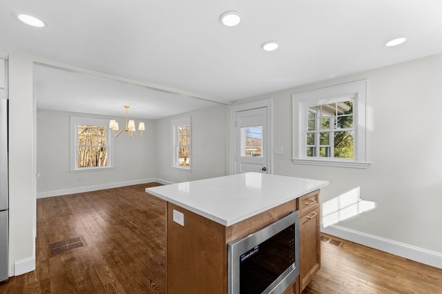 kitchen featuring a center island, a healthy amount of sunlight, hanging light fixtures, and dark wood-type flooring