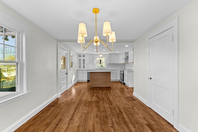 kitchen with dark wood-type flooring, white cabinets, pendant lighting, and an inviting chandelier