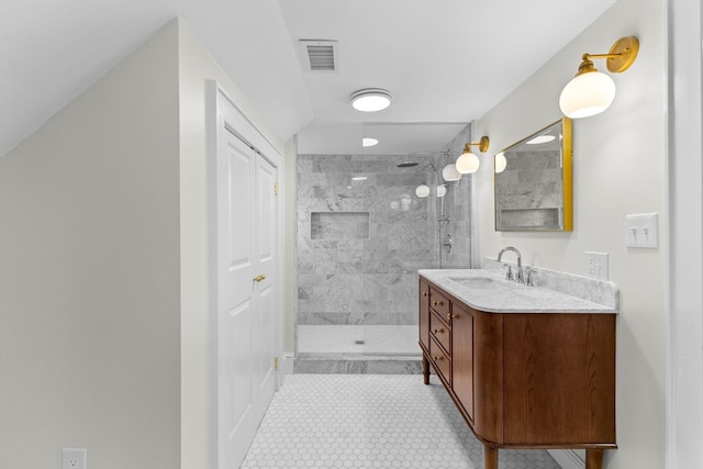 bathroom with a tile shower and vanity