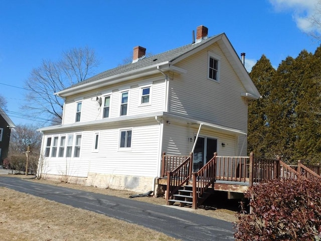 rear view of property featuring a deck and a chimney