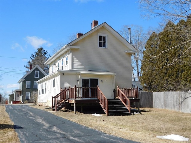 exterior space with a wooden deck, stairway, fence, and a chimney