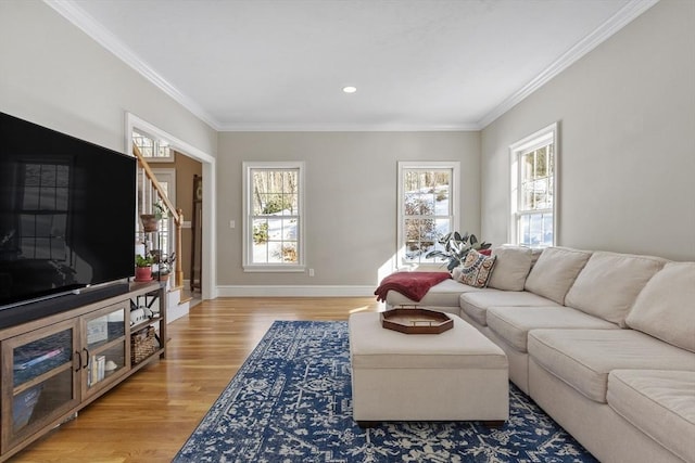 living room featuring baseboards, ornamental molding, stairway, and light wood-style floors