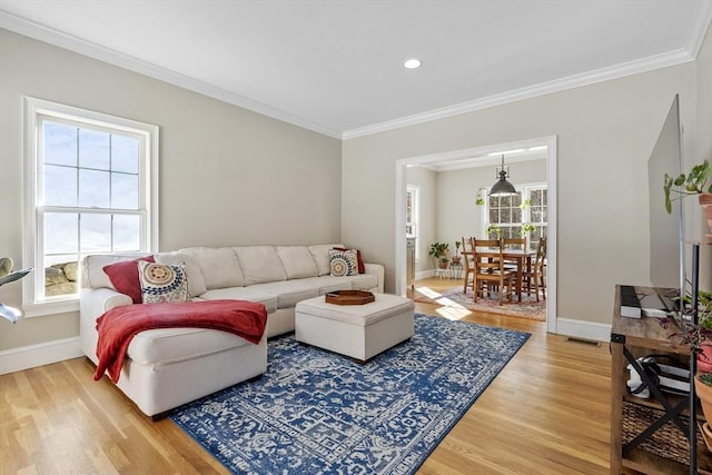 living area with light wood-type flooring, crown molding, and baseboards