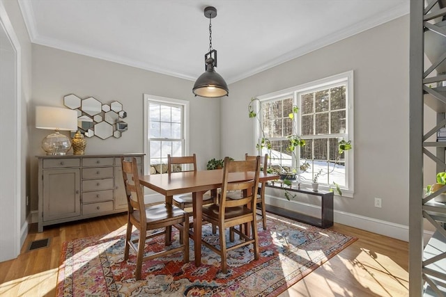 dining room featuring ornamental molding, a wealth of natural light, and light wood-style floors