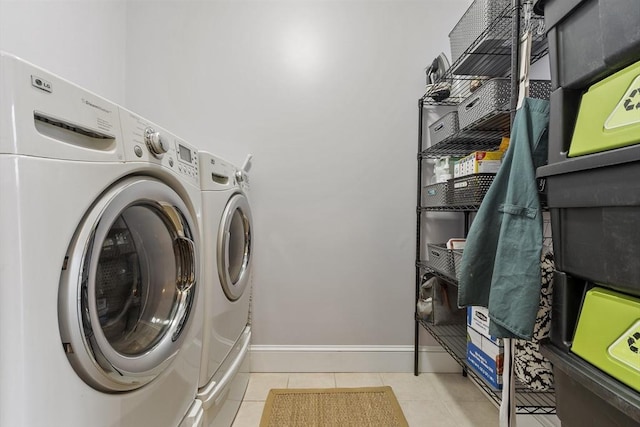 laundry area with laundry area, washer and clothes dryer, tile patterned flooring, and baseboards