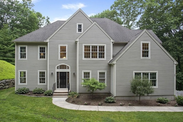 colonial inspired home featuring a front yard and roof with shingles