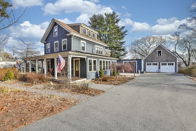 view of front facade with a garage, a porch, and an outbuilding