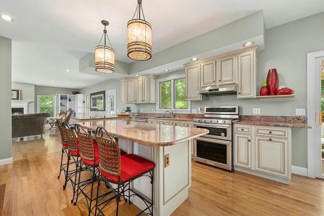 15 Keyes House Rd, Shrewsbury, MA 01545 - kitchen with cream cabinets, range with two ovens, under cabinet range hood, a kitchen breakfast bar, and light stone counters