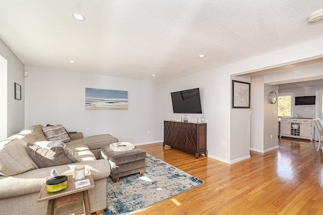 living area with a textured ceiling, baseboards, wood finished floors, and recessed lighting