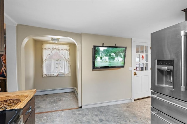 kitchen featuring stainless steel fridge, arched walkways, carpet, baseboards, and baseboard heating