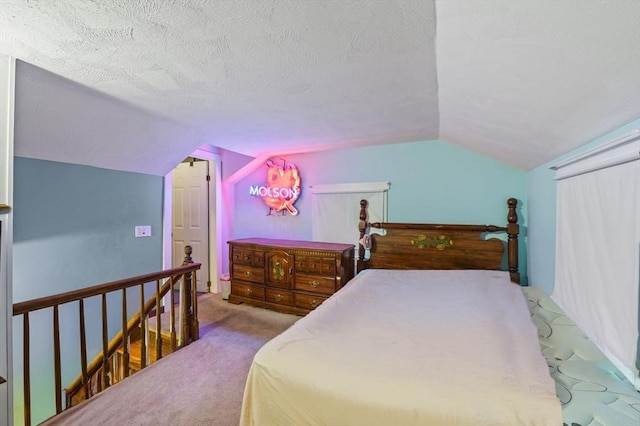 carpeted bedroom with a textured ceiling and vaulted ceiling