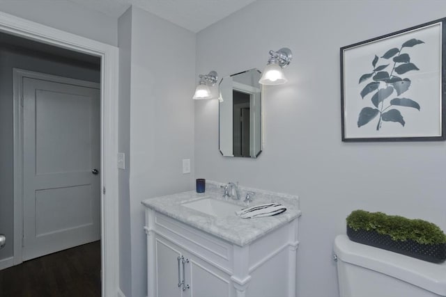 bathroom with hardwood / wood-style flooring, vanity, and toilet