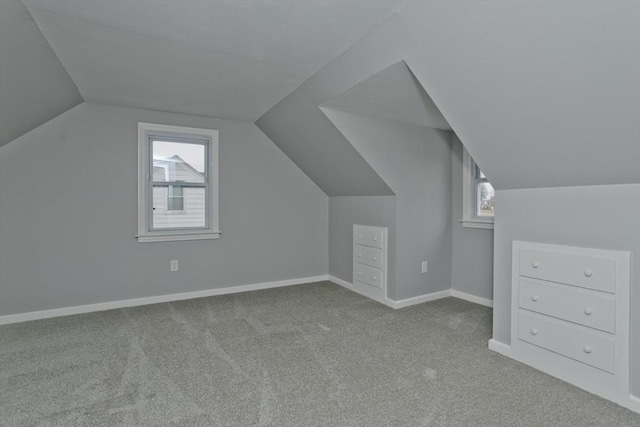 additional living space featuring light carpet, plenty of natural light, and lofted ceiling