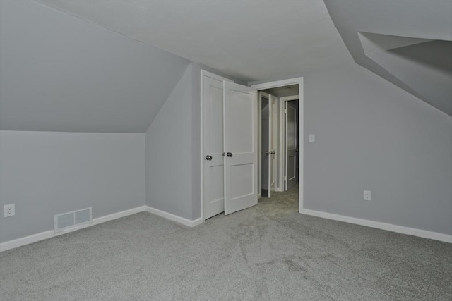 additional living space featuring light colored carpet and lofted ceiling