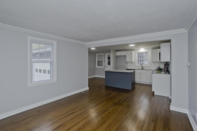 kitchen with white cabinets, decorative backsplash, a kitchen island, and crown molding