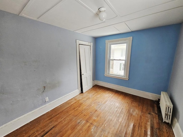 spare room featuring radiator, hardwood / wood-style flooring, and baseboards