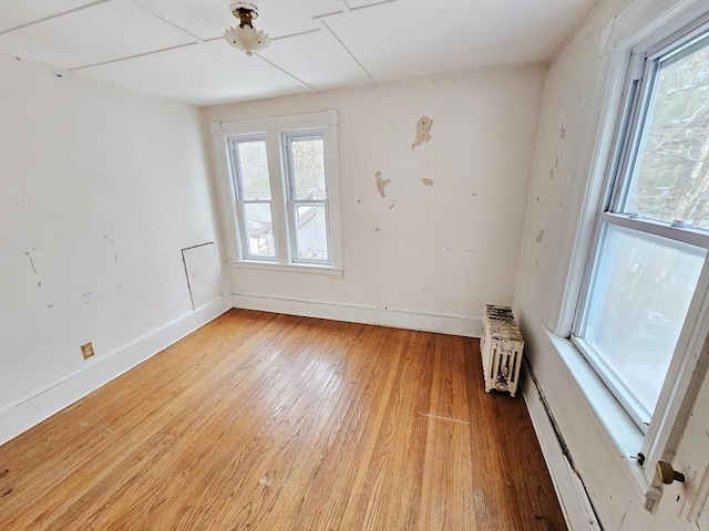 spare room with radiator, baseboards, and light wood-style flooring
