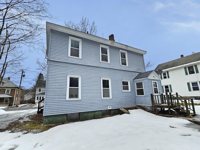 snow covered property featuring a chimney and a wooden deck