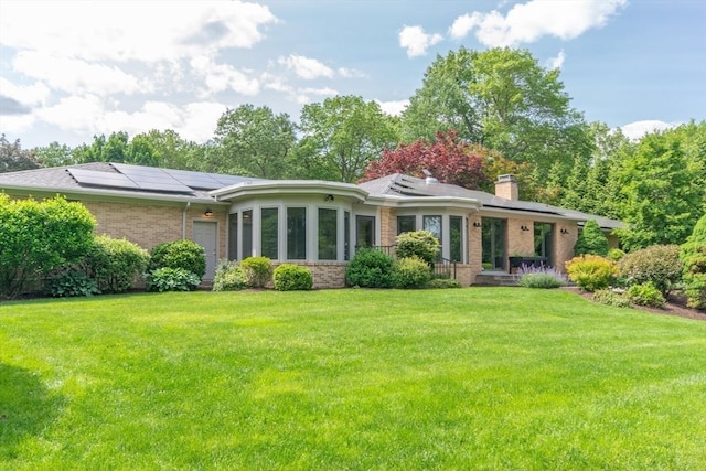 109 Wild Grove Ln, Longmeadow, MA 01106 - rear view of house with brick siding, roof mounted solar panels, a yard, and a chimney
