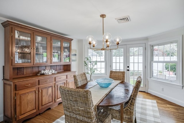 dining space with a chandelier, plenty of natural light, crown molding, light wood-style flooring, and baseboards