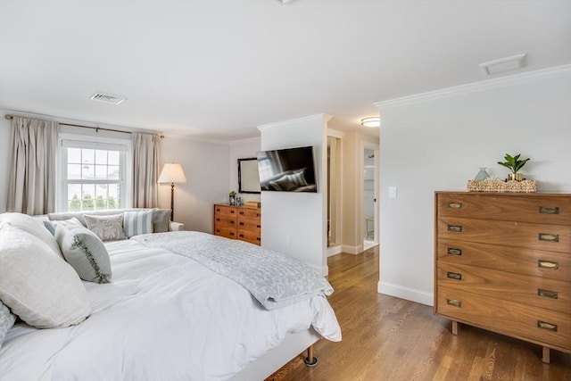 bedroom featuring wood finished floors, ornamental molding, baseboards, and attic access