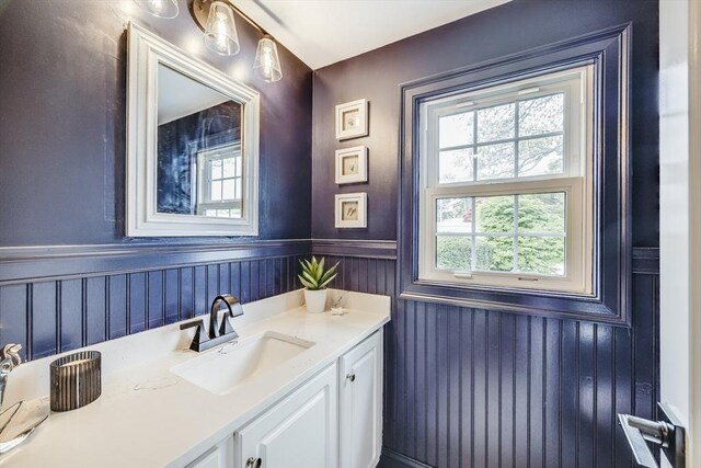 bathroom with healthy amount of natural light, a wainscoted wall, and vanity
