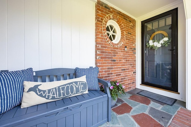 doorway to property featuring brick siding and a porch