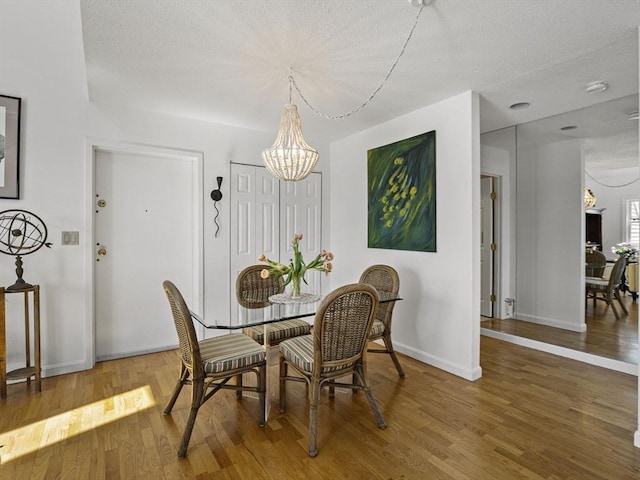 dining room featuring baseboards, an inviting chandelier, a textured ceiling, and wood finished floors