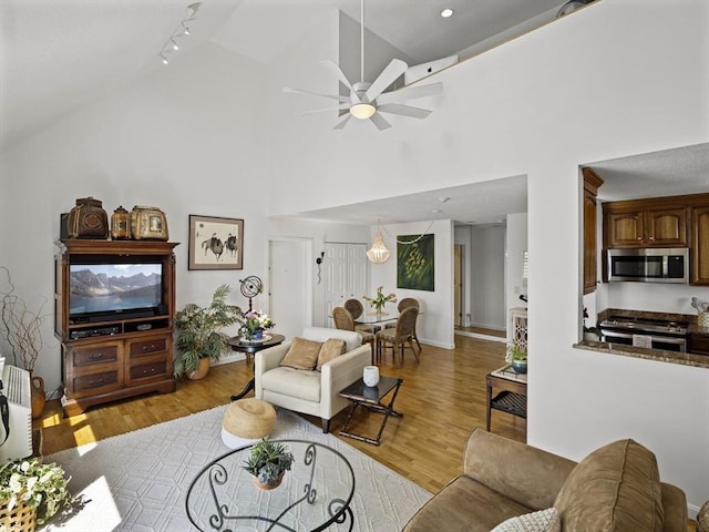 living area featuring light wood finished floors, ceiling fan, and high vaulted ceiling