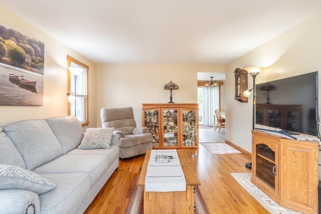 living room with a chandelier, light wood-style floors, and baseboards