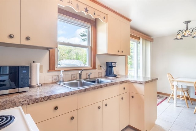 kitchen featuring a sink, a chandelier, light countertops, decorative light fixtures, and light tile patterned floors