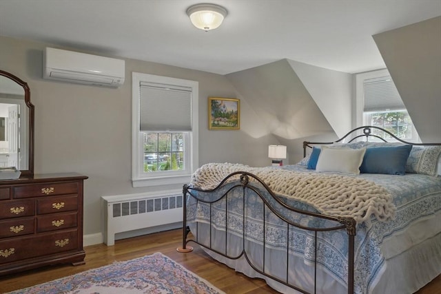 bedroom featuring a wall mounted air conditioner, radiator, baseboards, wood finished floors, and vaulted ceiling